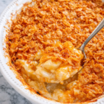 easy cheesy cornflake potato casserole with crispy topping and creamy potatoes in white dish on marble counter with spoon