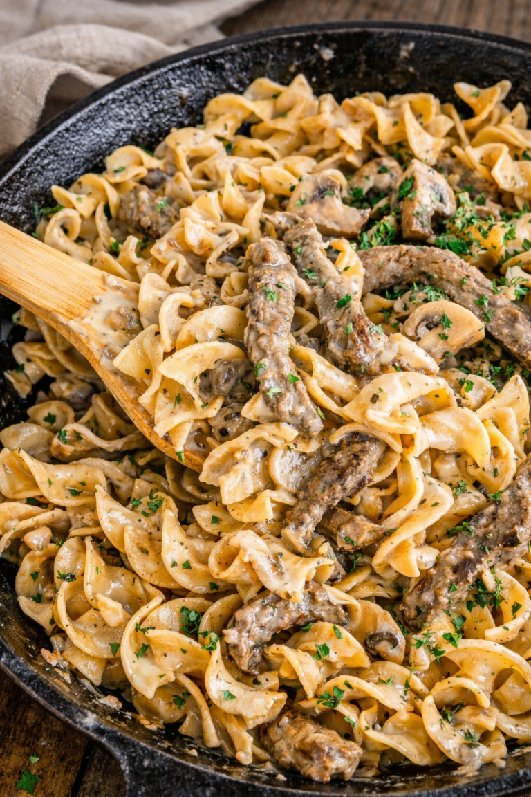 Creamy blue cheese beef stroganoff with mushrooms and egg noodles in a cast iron skillet