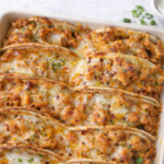 Baked chicken bacon ranch tacos with melted cheese in a white baking dish, oven baked until crispy and golden.