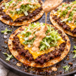 Crispy Big Mac tacos cooked in a skillet with browned flour tortillas, juicy smashed ground beef, melted American cheese, shredded lettuce, pickles, onions, and drippy special sauce.