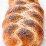 Golden braided poppy seed bread loaf with a soft interior and glossy crust, baked until perfectly golden brown
