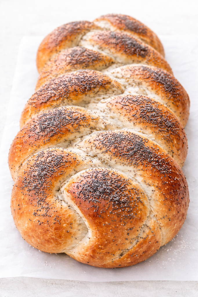 Golden braided poppy seed bread loaf with a soft interior and glossy crust, baked until perfectly golden brown