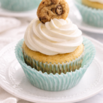 Chocolate chip cookie cupcake with vanilla frosting and mini cookie topper on a white plate