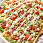 Chopped wedge pasta salad with elbow macaroni, romaine lettuce, crispy bacon, cherry tomatoes, blue cheese, and creamy wedge dressing in a white bowl.