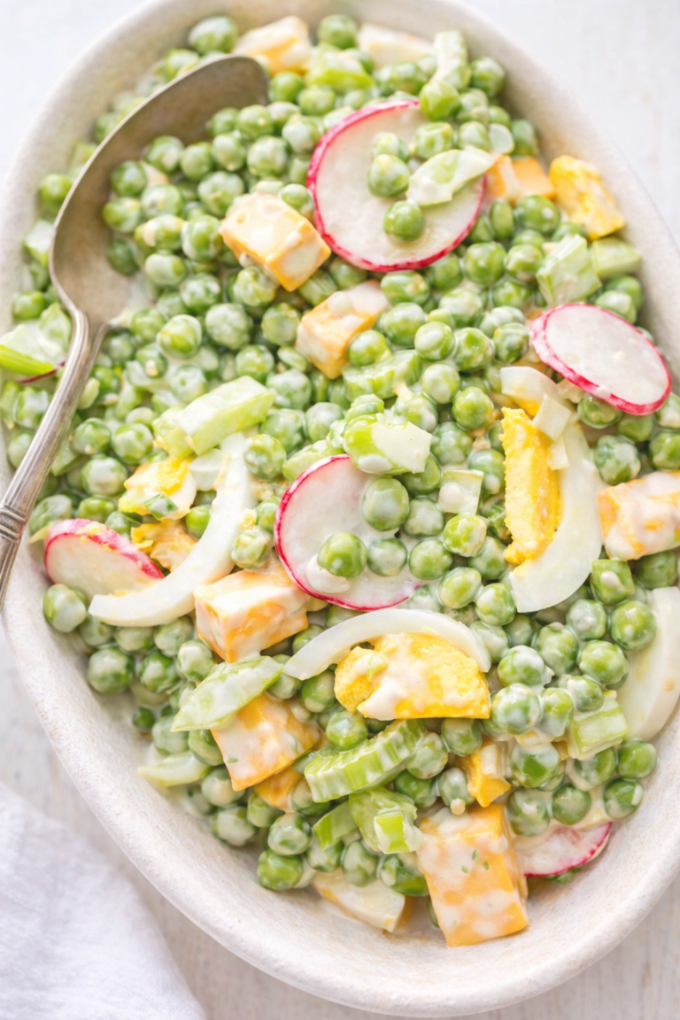 Classic pea and cheese salad made with green peas, cheddar cheese, hard-boiled eggs, celery, and radishes in a creamy dressing, served in a light bowl.