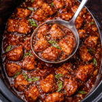 Slow cooker bourbon chicken coated in a thick glossy sauce with a ladle scooping tender chicken pieces