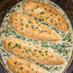 Creamy Boursin spinach chicken cooking in a crockpot with tender chicken breasts in a white wine cream sauce