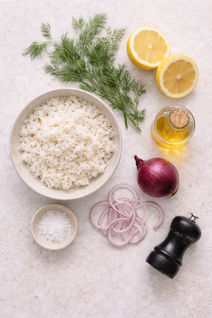 Easy herb rice salad ingredients flat lay with cooked rice, fresh dill, lemon, red onion, olive oil, salt, and pepper on a light neutral background