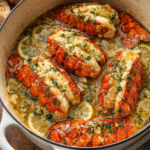 Garlic butter lobster tails dripping with rich butter sauce in a white enamel cast iron pot with crusty bread on the side