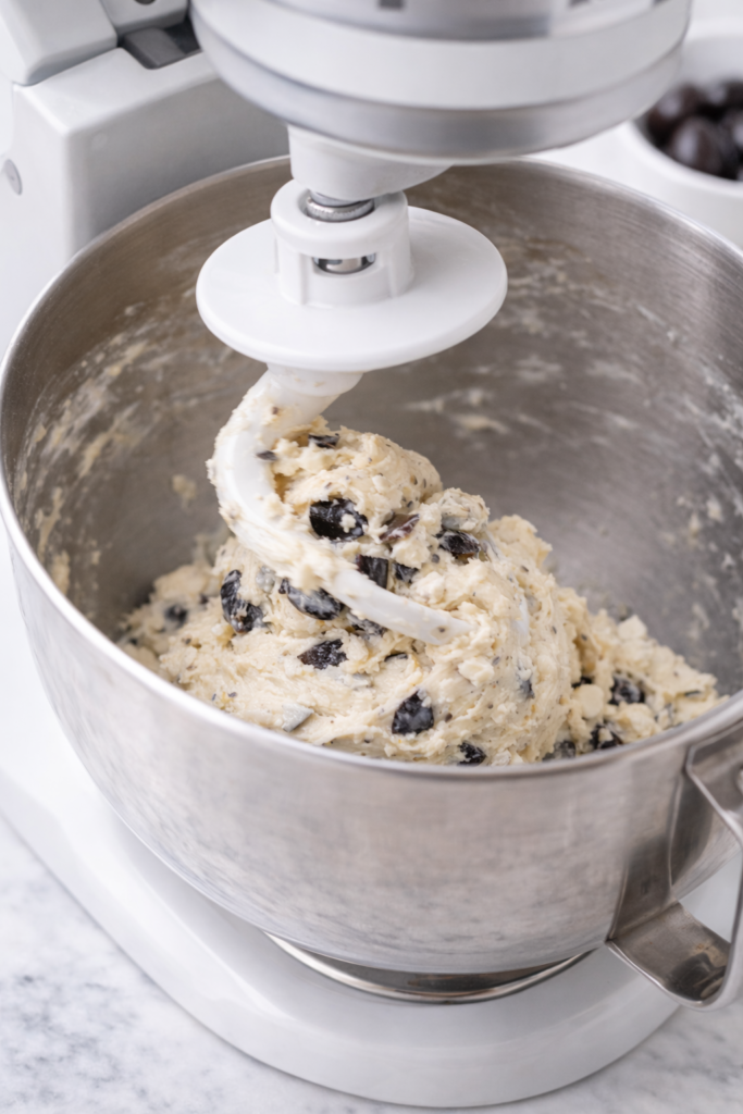 Greek olive and feta bread dough being mixed in a stand mixer with dough hook attachment