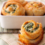 Golden baked Greek spinach cheese rolls with feta and spinach filling in a white baking dish
