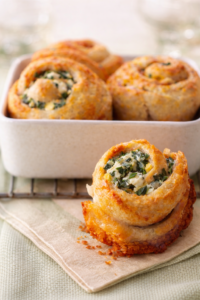 Golden baked Greek spinach cheese rolls with feta and spinach filling in a white baking dish