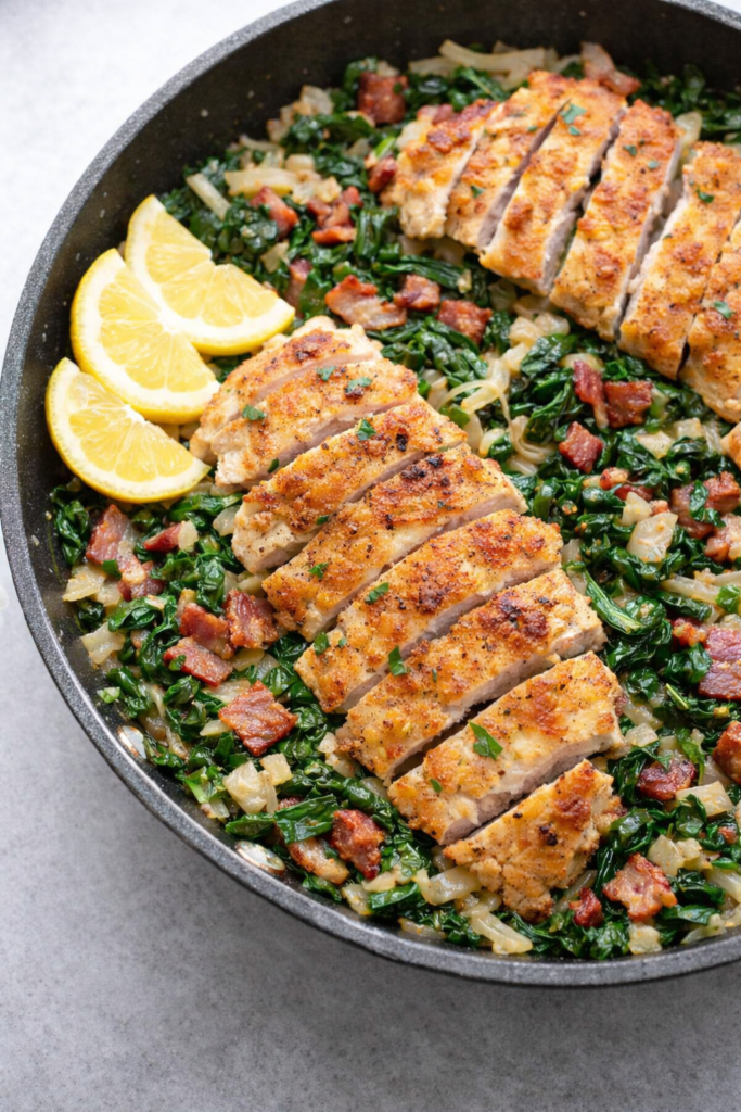 One-pan chicken scallopini with crispy breaded chicken cutlets, bacon, onions, and Swiss chard cooked in a skillet with lemon wedges.