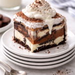 Slice of peanut butter chocolate cookie ice cream cake topped with whipped cream on stacked white plates