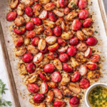 Roasted radishes with light char arranged on a parchment-lined baking sheet, seasoned with herbs and butter