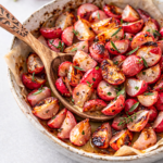 Roasted tarragon radishes with light char, butter, and fresh herbs served in a ceramic dish on a clean neutral table