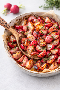 Roasted tarragon radishes with light char, butter, and fresh herbs served in a ceramic dish on a clean neutral table