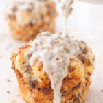 Light and fluffy breakfast sausage monkey muffin made with biscuit dough and cheese, topped with creamy sausage gravy being poured over the top.
