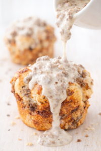 Light and fluffy breakfast sausage monkey muffin made with biscuit dough and cheese, topped with creamy sausage gravy being poured over the top.