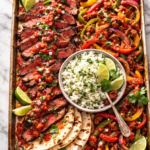 Sheet pan Southwestern steak with roasted peppers, chorizo, cilantro lime rice, and warm tortillas on a marble surface