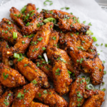Sheet pan Vietnamese-style sticky chicken wings baked until crispy and glazed with a sweet savory sauce on white parchment paper.