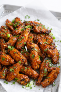 Sheet pan Vietnamese-style sticky chicken wings baked until crispy and glazed with a sweet savory sauce on white parchment paper.