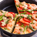 Shrimp and grits tart baked in a cast iron skillet with goat cheese, asparagus, tomatoes, and fresh dill