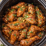 Slow cooker Thai peanut chicken wings coated in a rich peanut butter–brown coconut peanut sauce with cilantro and chopped peanuts