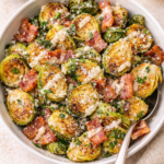 Roasted Brussels sprouts with bacon tossed in Caesar dressing and Parmesan cheese in a white serving bowl