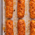 Buffalo chicken rollers baked on a parchment lined sheet pan with caramelized buffalo sauce