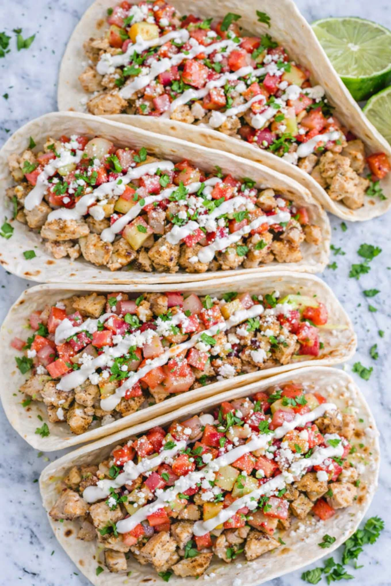 Chicken tacos topped with fresh rhubarb salsa, crema drizzle, and cotija cheese on a marble counter