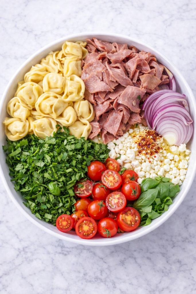 ingredients for chimichurri roast beef tortellini pasta salad in a bowl before mixing