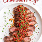 chimichurri rojo sauce over sliced steak on white plate with parsley and red pepper flakes