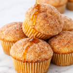 Cinnamon sugar French toast muffins with a maple syrup drizzle on top on a marble counter