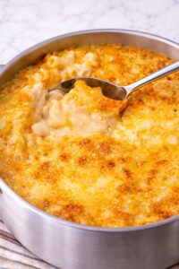 creamy baked mac and cheese with golden bubbly cheese crust in stainless steel pan