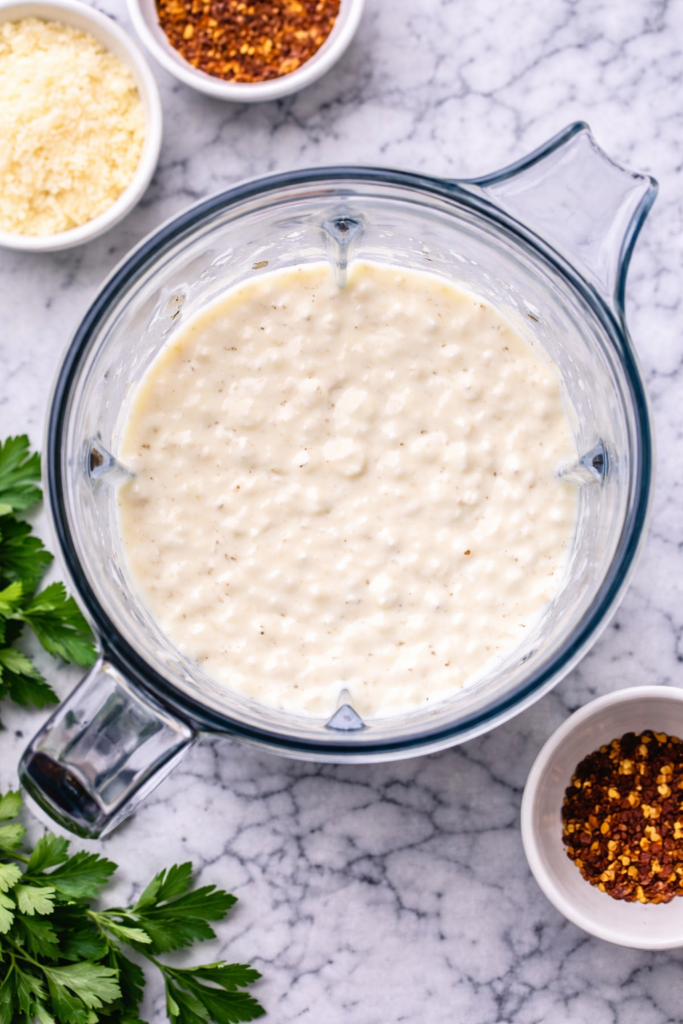 Birds eye view of cottage cheese Alfredo sauce blended in a blender on a marble countertop