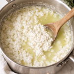 Fresh cottage cheese curds forming in whey in a pot during the cheese making process
