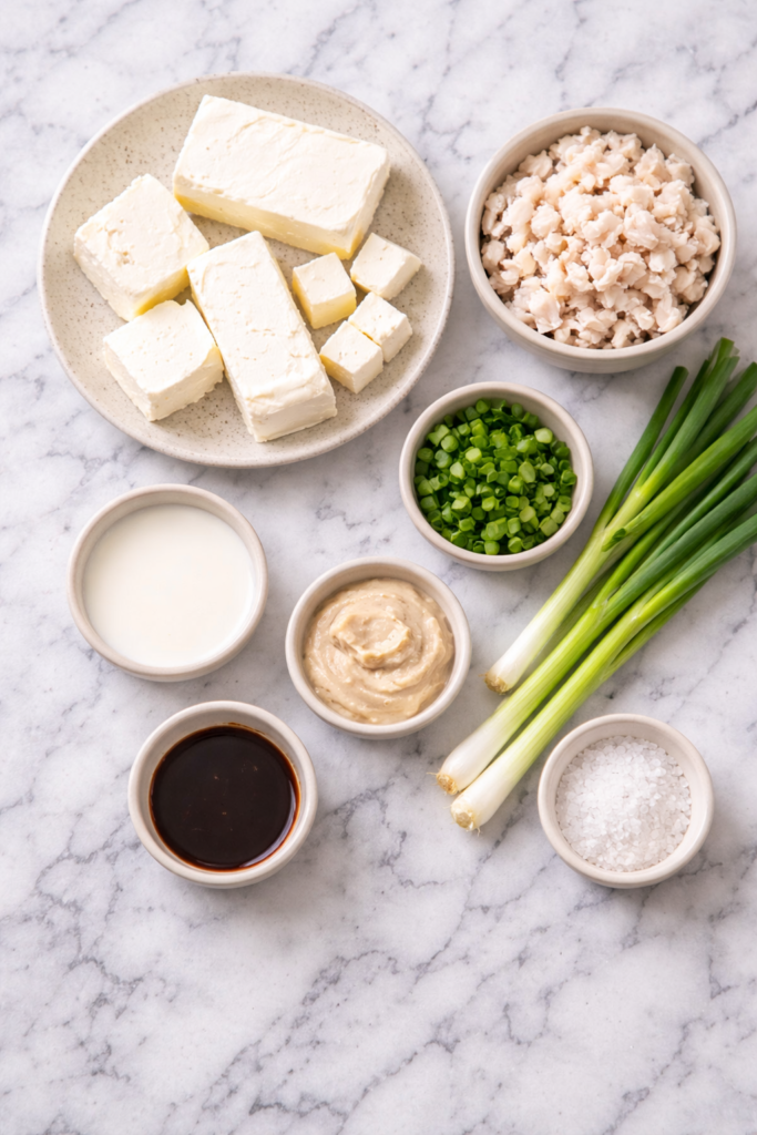 ingredients for crockpot crab dip including cream cheese, lump crab meat, green onions, milk, horseradish, and Worcestershire sauce