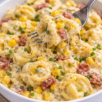 fork scooping creamy corn and bacon tortellini from white bowl on marble counter