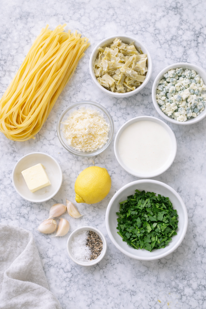 Flat lay of ingredients for creamy fettuccine with artichokes and blue cheese on a marble countertop