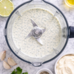 Birds-eye view of creamy garlic cilantro sauce blended in a blender on a marble countertop