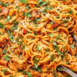 Creamy roasted red pepper chicken pasta with spaghetti, tender seasoned chicken, fresh basil, and grated parmesan cheese