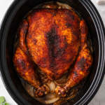 bird’s eye view of rotisserie style whole chicken cooked in crockpot on marble counter