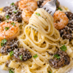 Fork twirling creamy shrimp pasta with mushrooms and Parmesan garlic sauce on a white plate