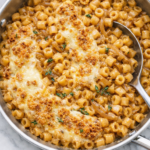creamy french onion pasta with ditalini in beef broth sauce topped with melted gruyere and toasted breadcrumbs in stainless skillet