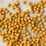 Crispy garlic and herb baked chickpeas roasted on a parchment lined baking sheet with dried herbs sprinkled on top