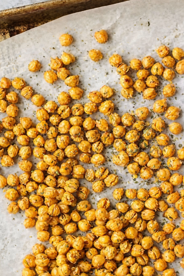 Crispy garlic and herb baked chickpeas roasted on a parchment lined baking sheet with dried herbs sprinkled on top
