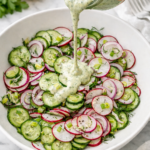 green goddess cucumber salad with radishes and red onion topped with creamy herb dressing