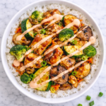 Hibachi chicken and vegetables served over white rice in a bowl drizzled with yum yum sauce