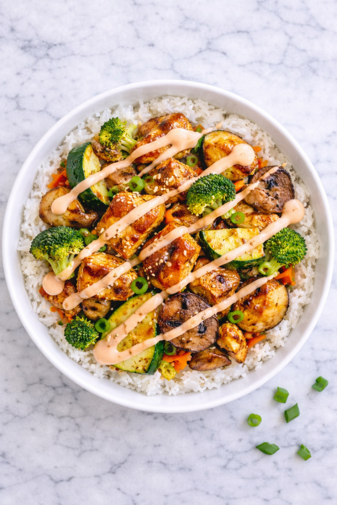 Hibachi chicken and vegetables served over white rice in a bowl drizzled with yum yum sauce